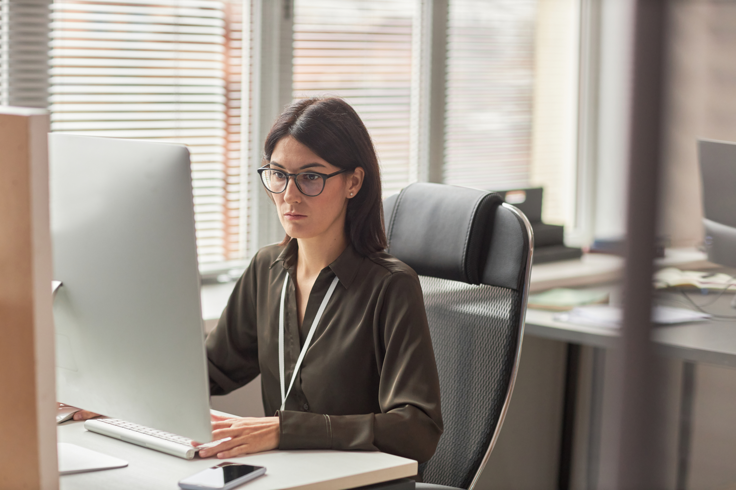 Businesswoman wearing glasses while using computer at workplace in office