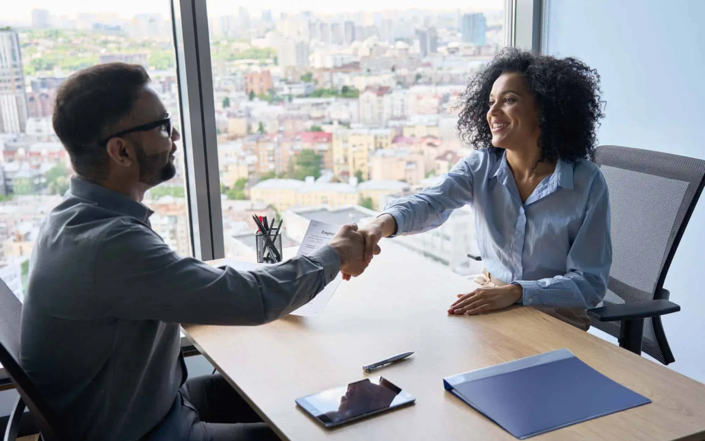 In a successful interview, the atmosphere is filled with mutual satisfaction. The manager and candidate smile, exchanging a firm handshake to mark the positive outcome. The manager’s demeanor is welcoming and approving, while the candidate’s expression shows relief and excitement.